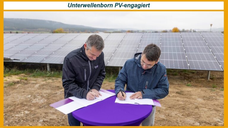 Stefan Zaubitzer (links) und Bürgermeister André Gölitzer unterzeichnen vor Solarmodulen einen Vertrag zur Photovoltaikanlage.
