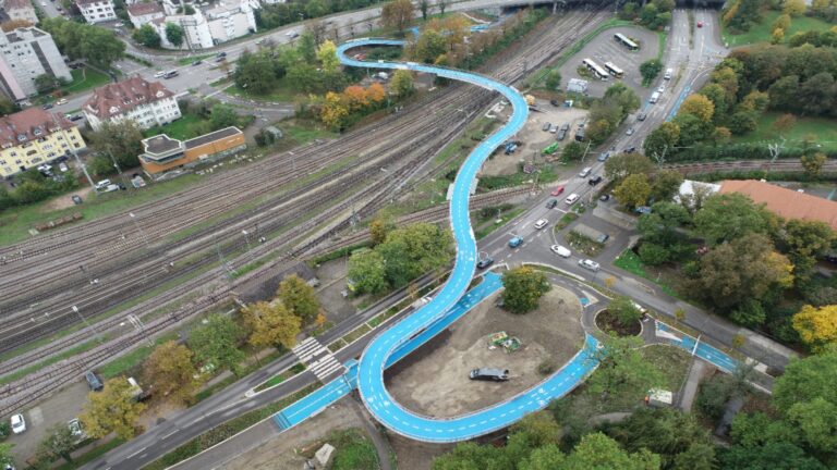 Luftaufnahme der Fahrradbrücke West „Ann Arbor Bridge“ in Tübingen, umgeben von grünen Landschaften.