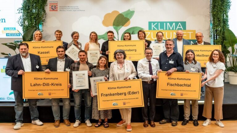 Ausgezeichnete Vertreterinnen und Vertreter hessischer Kommunen mit Ortsschildern zur „Klimakommune“ bei Preisverleihung.