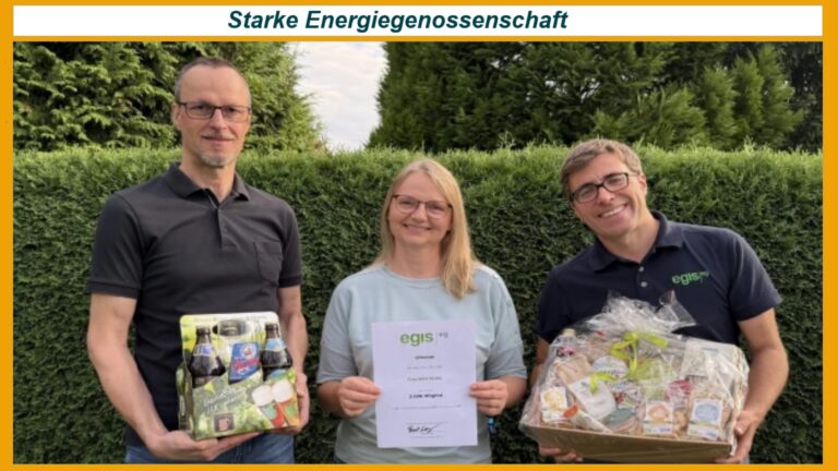 Pascal Lang gratuliert Irina Riedel als 3.000. Mitglied der EGIS eG, flankiert von Uwe Riedel, Energiegenossenschaft, Photovoltaik- und Energiespeicherprojekte im Hintergrund.