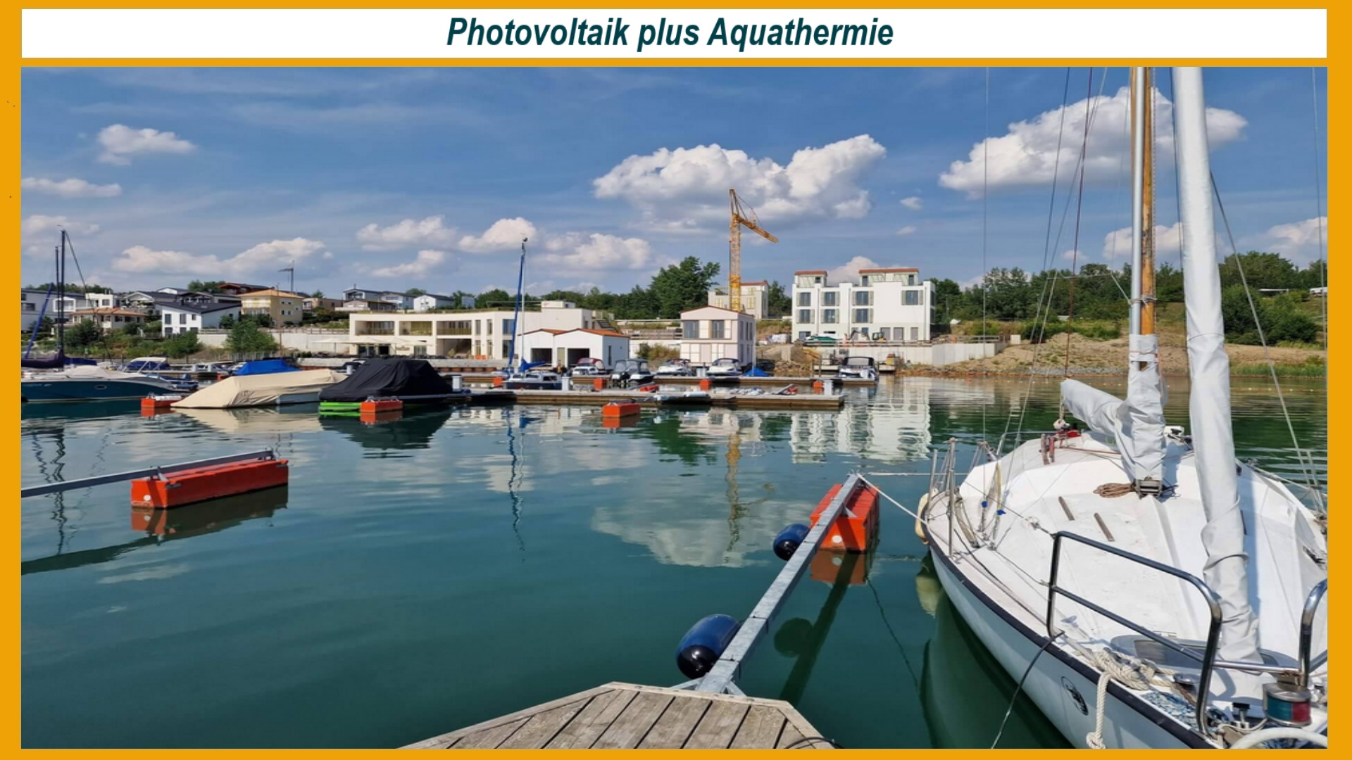 Hafen am Hainer See mit Wärmetauscheranlagen, die Aquathermie nutzen, im Hintergrund moderne Quartiersgebäude, Photovoltaik-Dächer und grünes Umfeld, innovative erneuerbare Energieversorgung sichtbar.