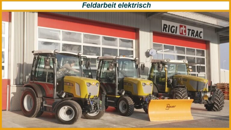 Drei gelbe RigiTrac-Traktoren vor einer Werkstatthalle mit rotem Tor, einer trägt ein orangefarbenes Schneeschild.