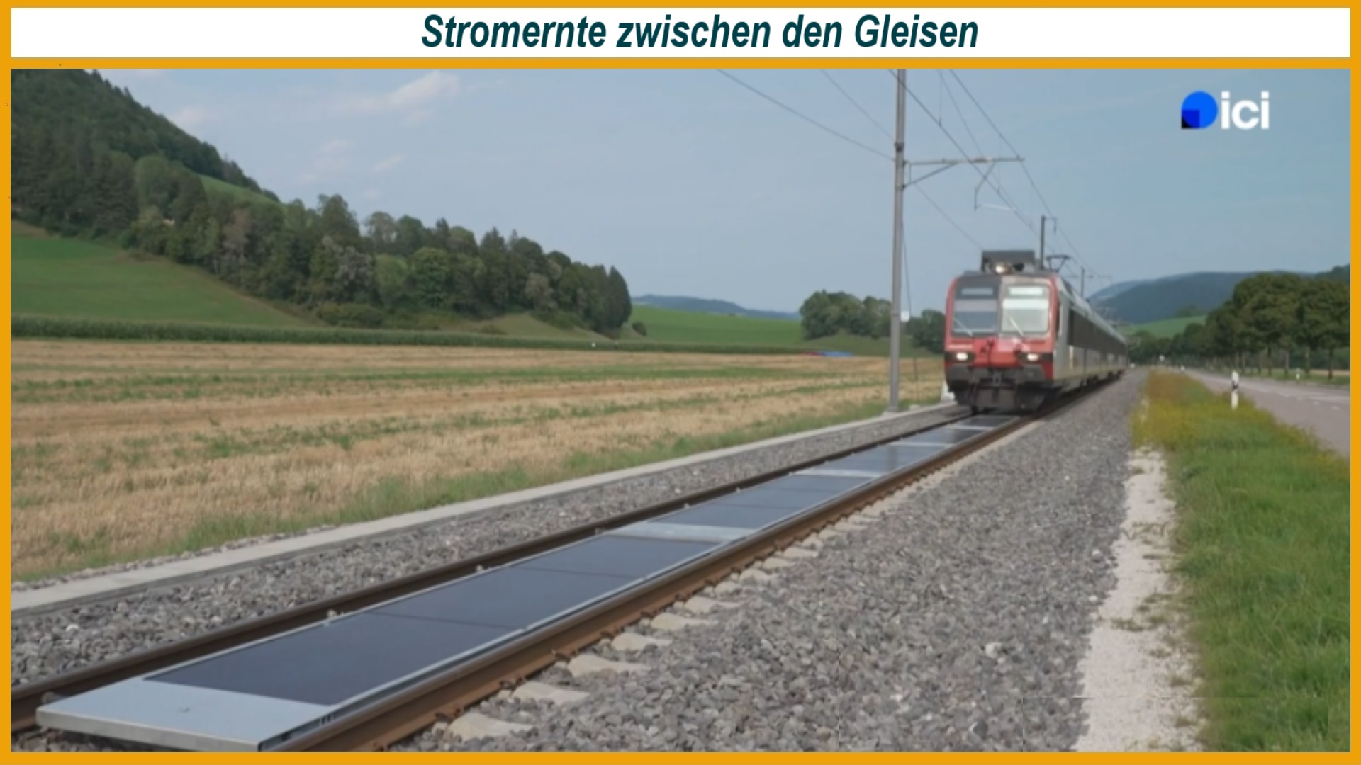 Ein Zug fährt auf einer Bahnstrecke mit zwischen den Schienen installierten Solarmodulen auf die Kamera zu. Das Schweizer Pilotprojekt zeigt die Nutzung von Bahngleisen zur Solarstromerzeugung.